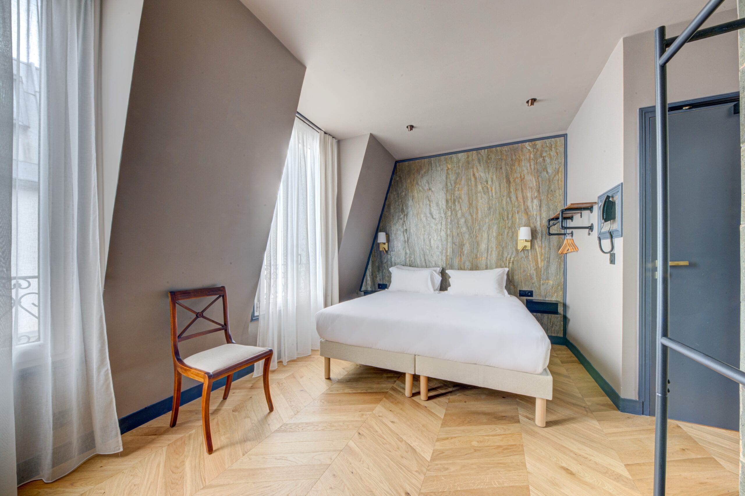Chambre de l’Hôtel Maât Batignolles, parquet à chevrons et lumière naturelle